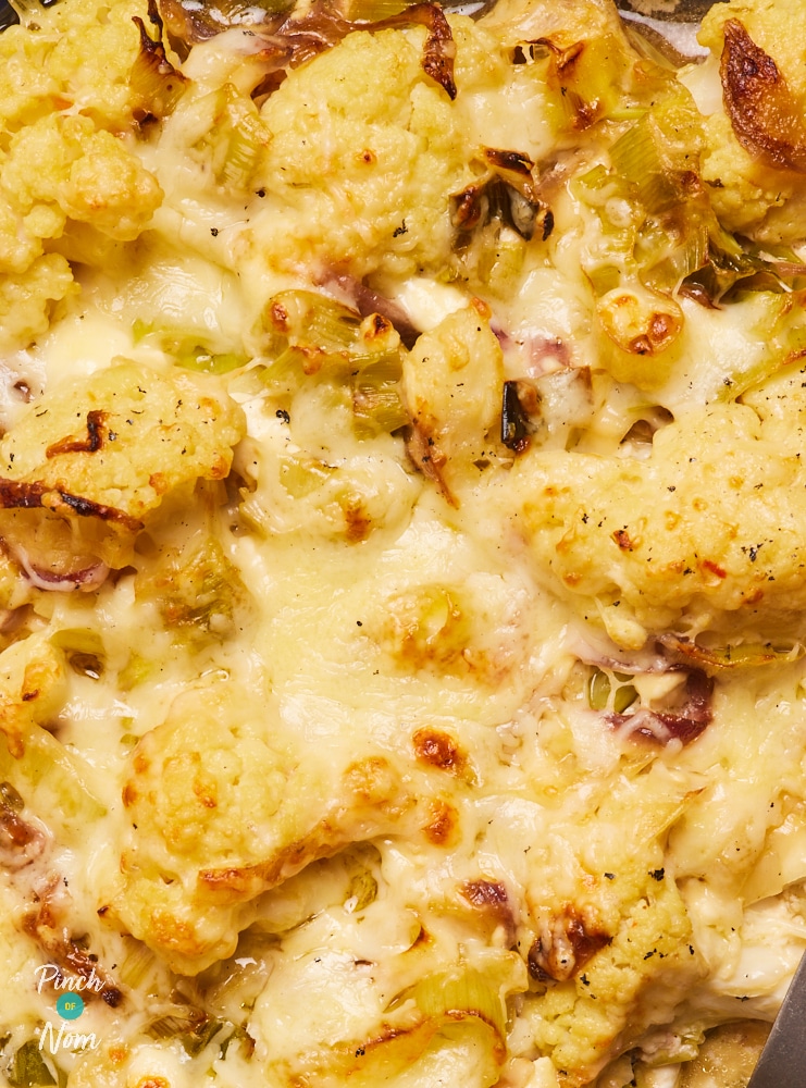 A close-up shows Pinch of Nom's Cauliflower Cheese fresh from the oven. The Cheddar cheese topping is melted and gooey, and the cauliflower is golden brown.