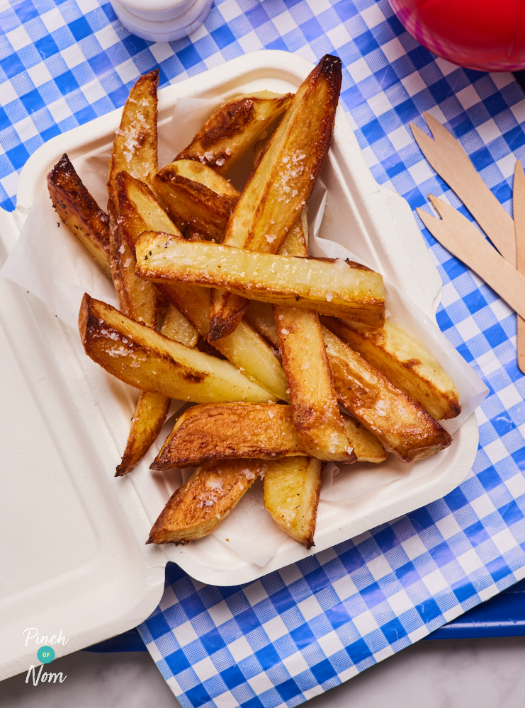 A close-up of a crispy portion of Pinch of Nom's Chunky Chips served in a paper tray with chippy-style wooden cutlery, ready to tuck in.