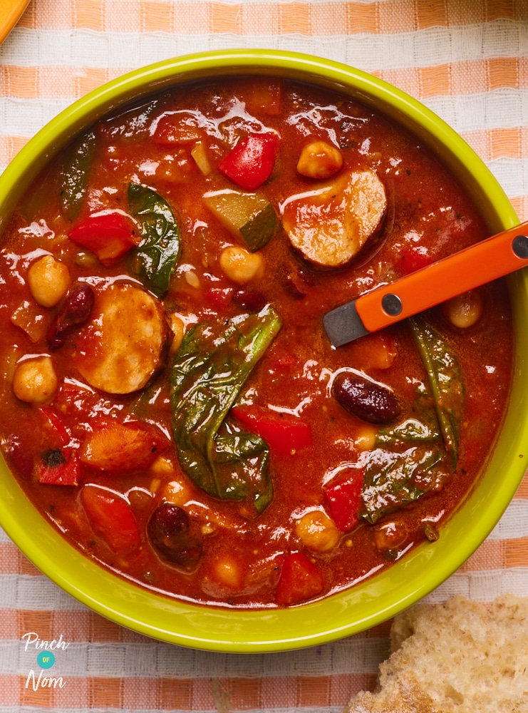 A bright yellow bowl is filled with Pinch of Nom's Slimming-friendly Slow Cooker Chunky Tomato Cajun-Style Soup.