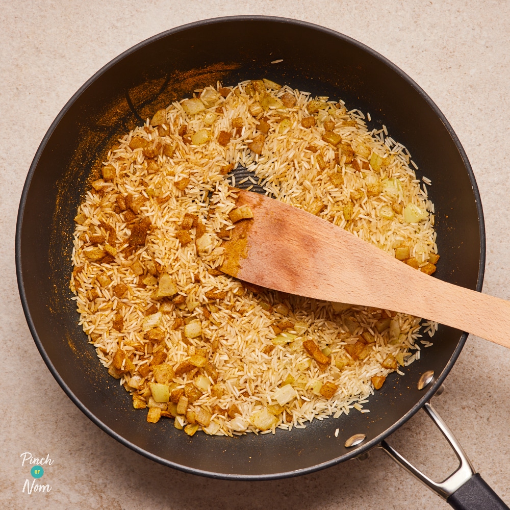 Curry powder and rice in large frying pan.