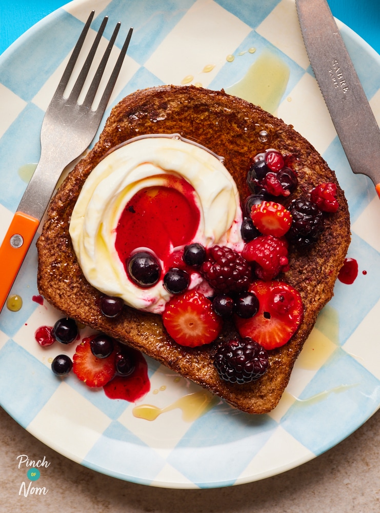 Pinch of Nom's French Toast, served on a plate and topped with berries and cream.