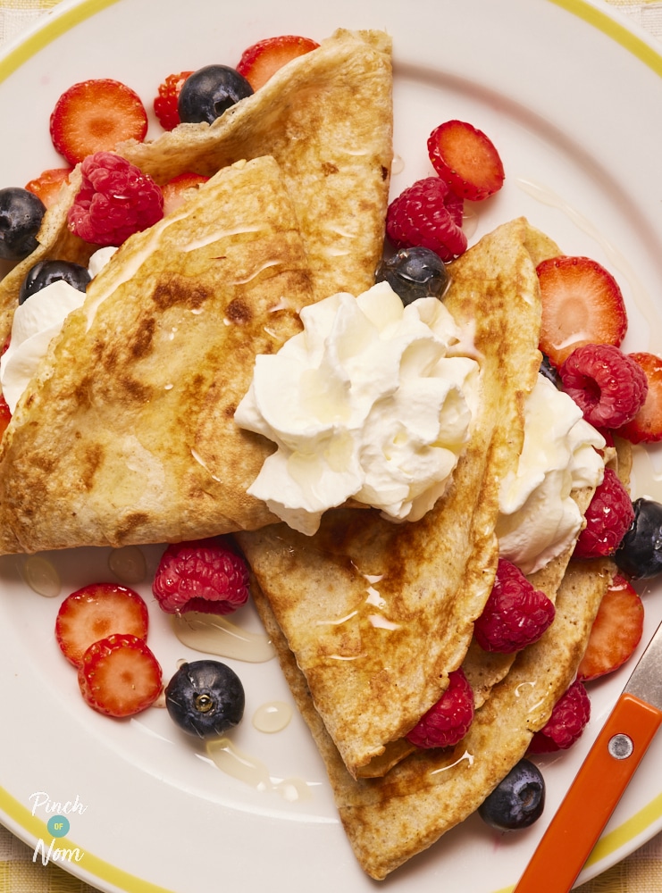 Pinch of Nom Folded Berry Pancake, served on a plate and topped with cream and fruit.