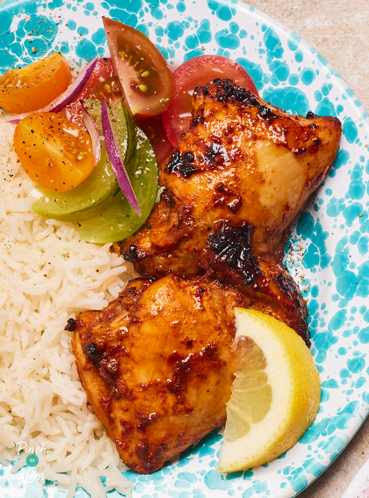 A close-up shows Pinch of Nom's Cajun-Style Chicken Thighs served with rice and vegetables. The chicken looks tender and juicy, with charred spices on the outside.