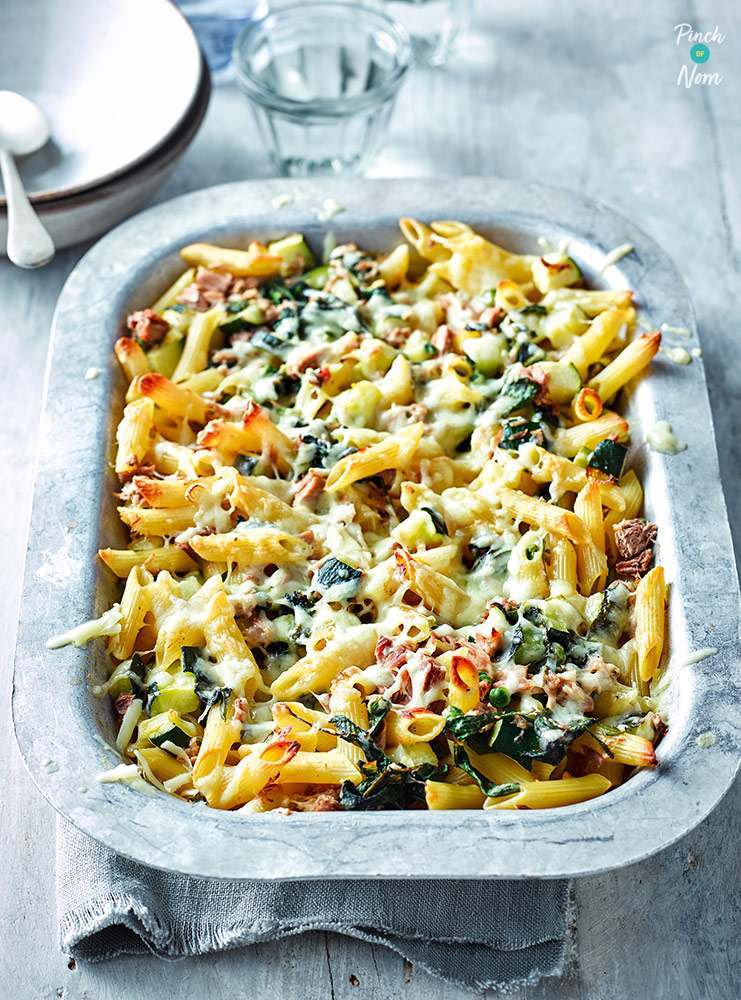 Pinch of Nom's Tuna Pasta Bake is fresh from the oven, in a rectangular oven dish. The pasta is golden and crunchy at the edges, with melted cheese on top. The creamy filling and spinach can be seen peeking through the topping. 