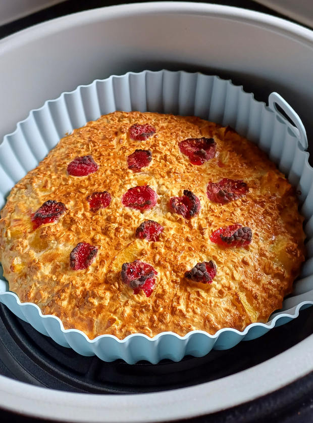 An image of Pinch of Nom's Peach Melba Baked Oats, uploaded by DebiT to the Pinch of Nom website gallery. The oats have been browned until golden in an air fryer and topped with raspberries.