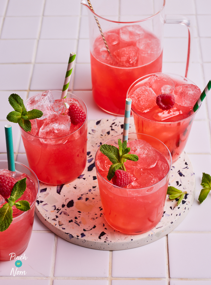 Pinch of Nom's Pink Lemonade is served in 4 glasses over ice with striped paper straws, fresh raspberries and a sprig of fresh mint.