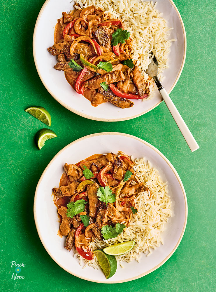 2 portions of Pinch of Nom's Creamy Chipotle Beef from Express are plated up on a bright green tabletop with lime wedges scattered on top and to the side, ready to be squeezed over. 