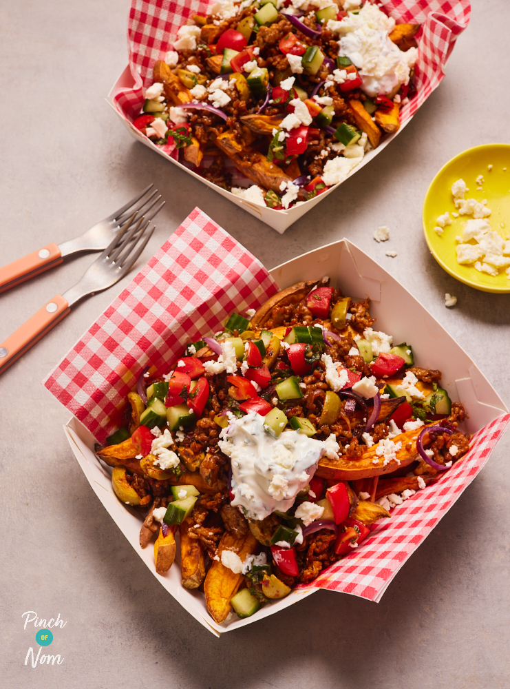 Takeaway style food cartons are filled with Pinch of Nom's Loaded Lamb Sweet Potato Fries. The golden fries are topped with lamb mince, chopped vegetables and crumbled feta cheese.