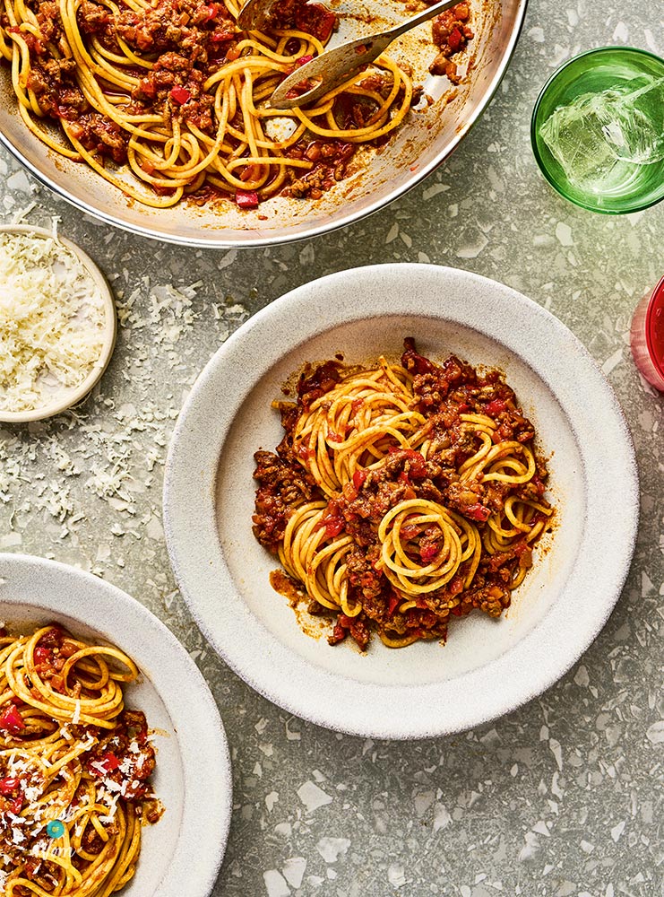 A large serving dish full of Pinch of Nom's BBQ Bolognese is to the side, while two platefuls are already served up.