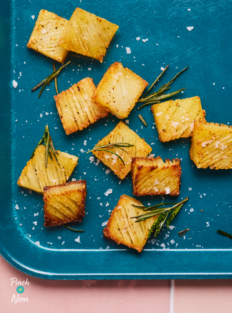 A tray of golden brown Accordion Potatoes. The rectangular potatoes are crispy at the edges, sprinkled with sea salt and fresh herbs.