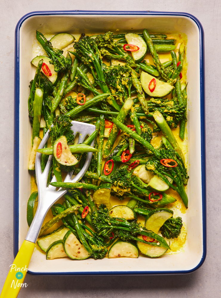 A tray of Chilli Roasted Greens is ready to serve. Courgette, broccoli, green beans and asparagus have been roasted in a spicy marinade, with slices of red chillies.