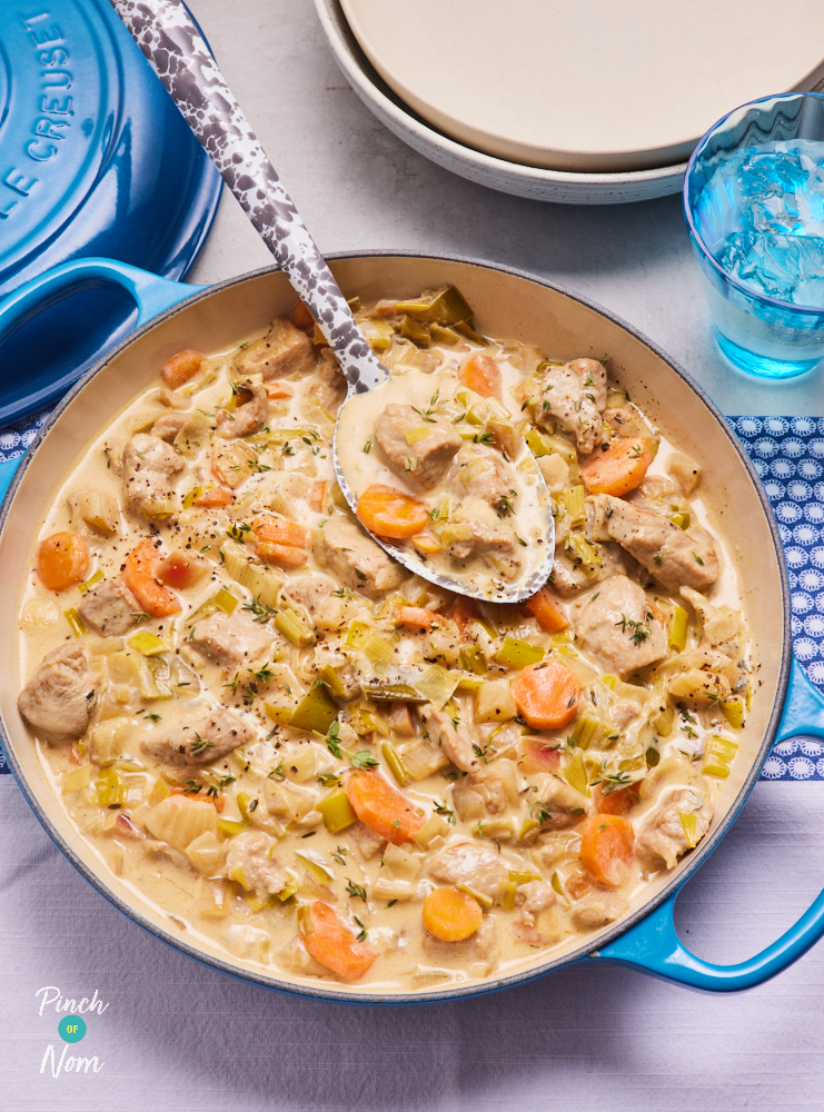 A large serving spoon picks up a creamy scoop of Pinch of Nom's Somerset Pork from a large blue casserole dish.