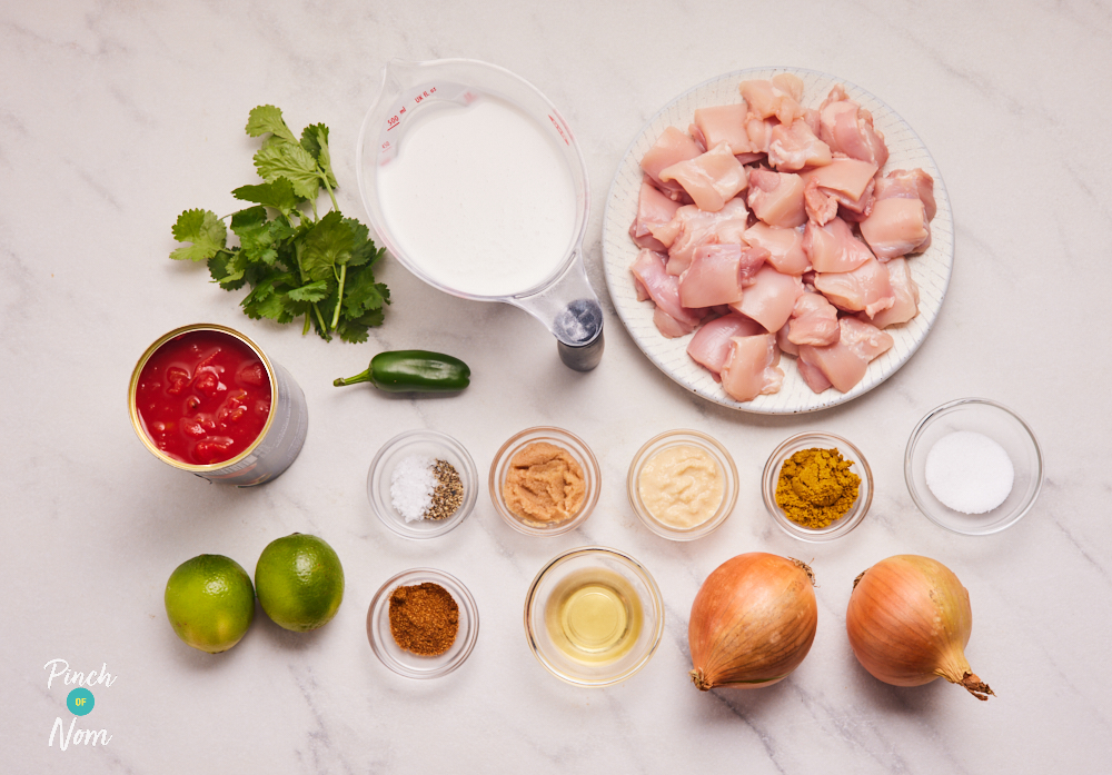 The uncooked ingredients for Pinch of Nom's Spicy Coconut and Lime Chicken Curry are laid out on a worktop.
