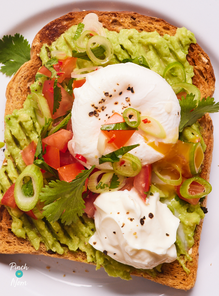 A close-up shows Pinch of Nom's easy brunch recipe for Tex Mex Toast. A perfectly poached egg is oozing yellow yolk onto the tomato salsa, smashed avocado and crisp wholemeal toast.