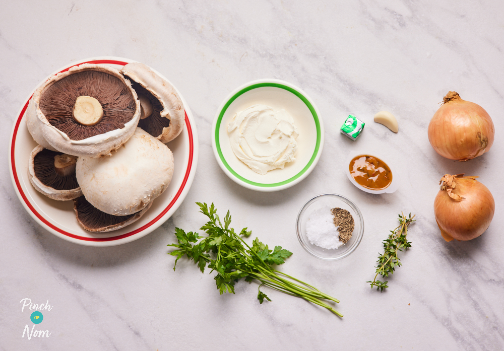The ingredients for Pinch of Nom's low-calorie Cream of Mushroom Soup are laid out on a counter top. There is mushrooms, fresh thyme, garlic, a stock cube, a stock pot, fresh parsley, cream cheese and salt and pepper.