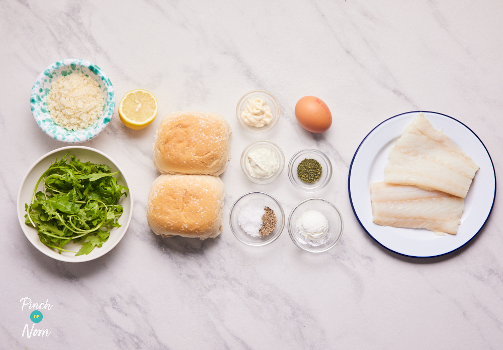 The ingredients for Pinch of Nom's Crispy Fish Burgers are laid out on a kitchen counter. Cod fillets, egg, panko breadcrumbs, parsley, breadcrumbs, mayonnaise, salt and pepper are set out ready to cook the healthy family recipe.