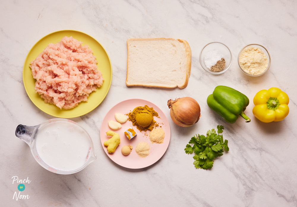 The ingredients for Pinch of Nom's Korma Meatballs are laid out on a kitchen counter. Chicken mince, an onion, green pepper, yellow pepper, a slice of bread, coconut milk alternative and various herbs and spices are set out ready to cook the healthy family recipe.