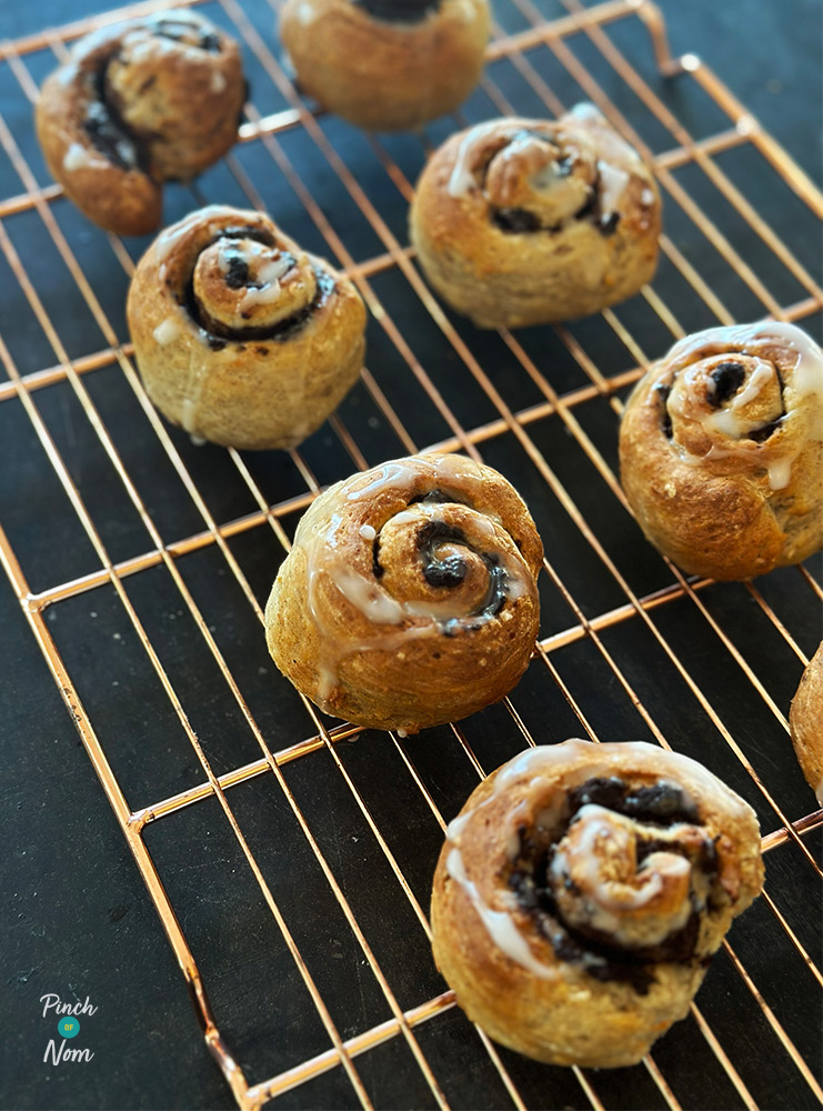 Pinch of Nom's Air Fryer Cinnamon Breakfast Buns are on a cooling rack, ready to be enjoyed. They're topped with a homemade vanilla icing glaze and swirled through with a cinnamon filling.