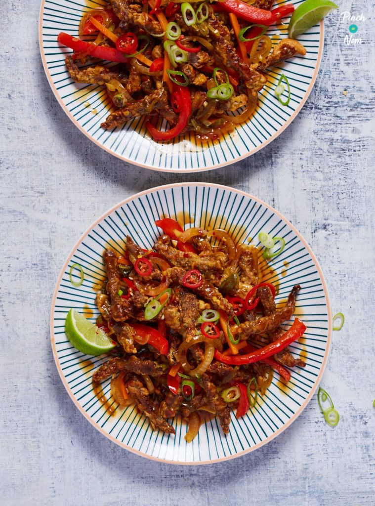 Two plates of Pinch of Nom's slimming-friendly Air Fryer Crispy Chilli Beef are served on a grey worktop.