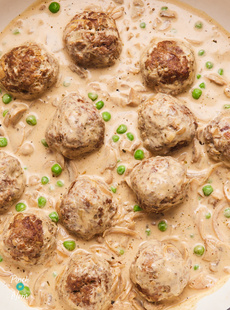 A close up of Pinch of Nom's slimming friendly Creamy Dijon Meatballs. The sauce is pale and creamy, with pops of bright green peas. The homemade meatballs are golden brown and nestled in the silky sauce.