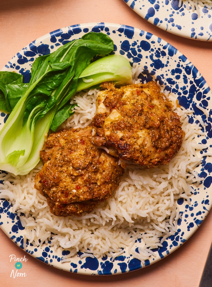 A close-up image of Pinch of Nom's Thai-Style Aromatic Baked Chicken plated up over a fluffy portion of basmati rice and stir-fried pak choi.