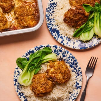 A table is set for two with Pinch of Nom's Thai-Style Aromatic Baked Chicken plated up over a fluffy portion of basmati rice and stir-fried pak choi.
