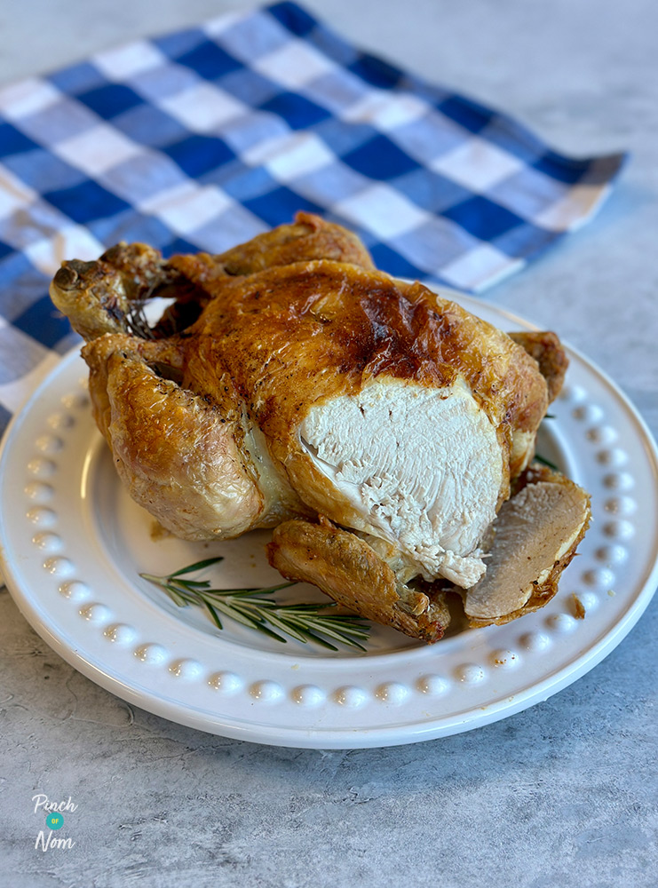 Pinch of Nom's slimming-friendly Air Fryer Whole Chicken from the Air Fryer cookbook is being carved on a plate.
