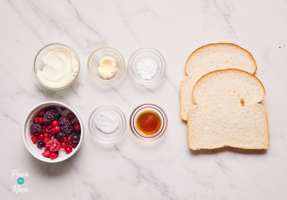 The ingredients for Pinch of Nom's Berry Toastie are laid out on a kitchen counter. All the ingredients are measured out, waiting in small glass bowls, ready to begin cooking.