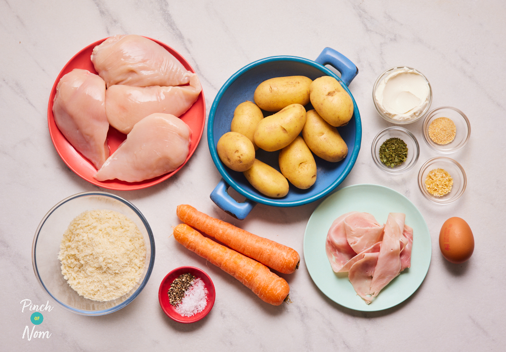 The ingredients for Pinch of Nom's Chicken Kyiv Traybake are laid out on a kitchen counter. The ingredients are measured out and presented on an array of plates and in small bowls, ready to begin cooking.