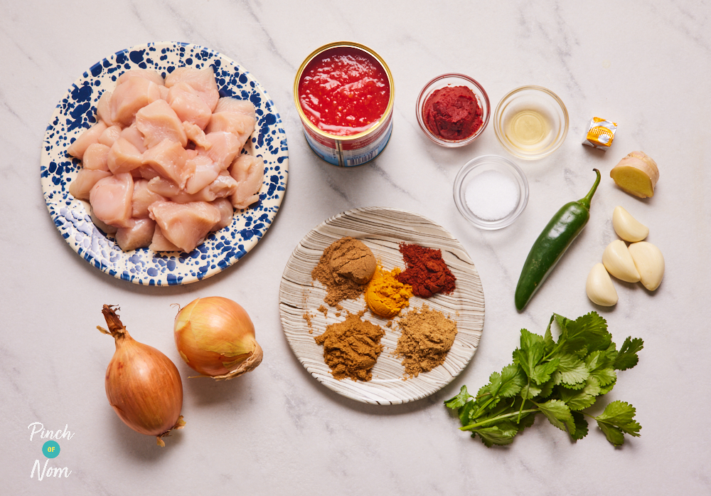 The ingredients for Pinch of Nom's Chicken Madras are laid out on a kitchen countertop, ready to start cooking.