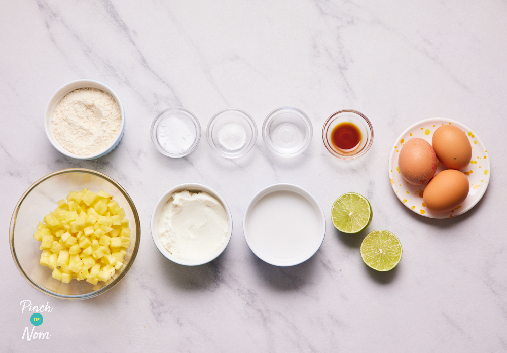 The ingredients for Pinch of Nom's Piña Colada Pancakes are set out on a kitchen worktop. Each ingredient is portioned out and ready in an individual bowl, waiting to begin cooking.