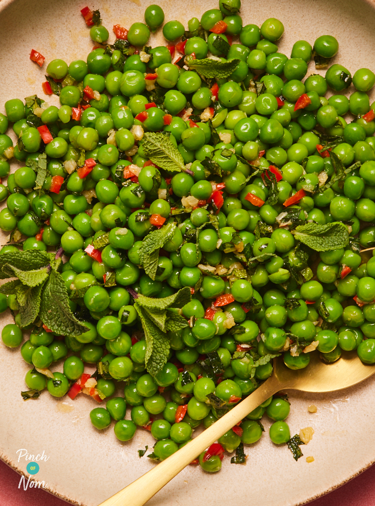 A close-up image of Pinch of Nom's Chilli and Mint Peas served on a blush pink plate with a gold spoon waiting to tuck in.