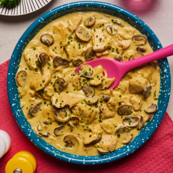 A plate of Creamy Garlic Chicken made with the Flava It! X Pinch of Nom recipe mix is served on a table set for dinner.