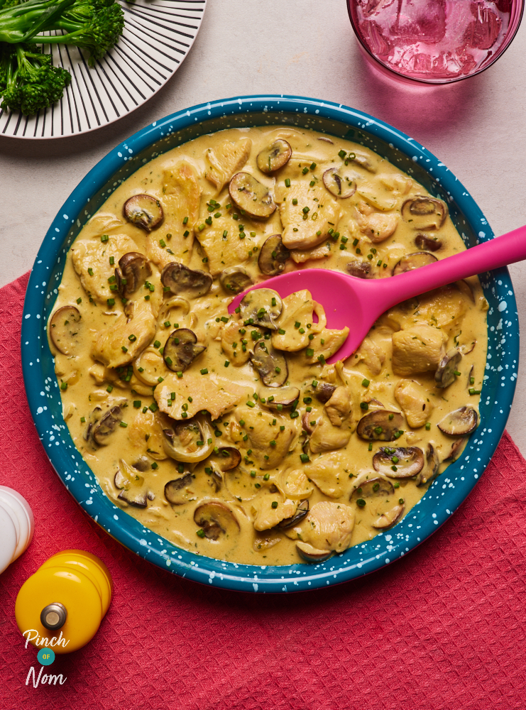 A plate of Creamy Garlic Chicken made with the Flava It! X Pinch of Nom recipe mix is served on a table set for dinner.