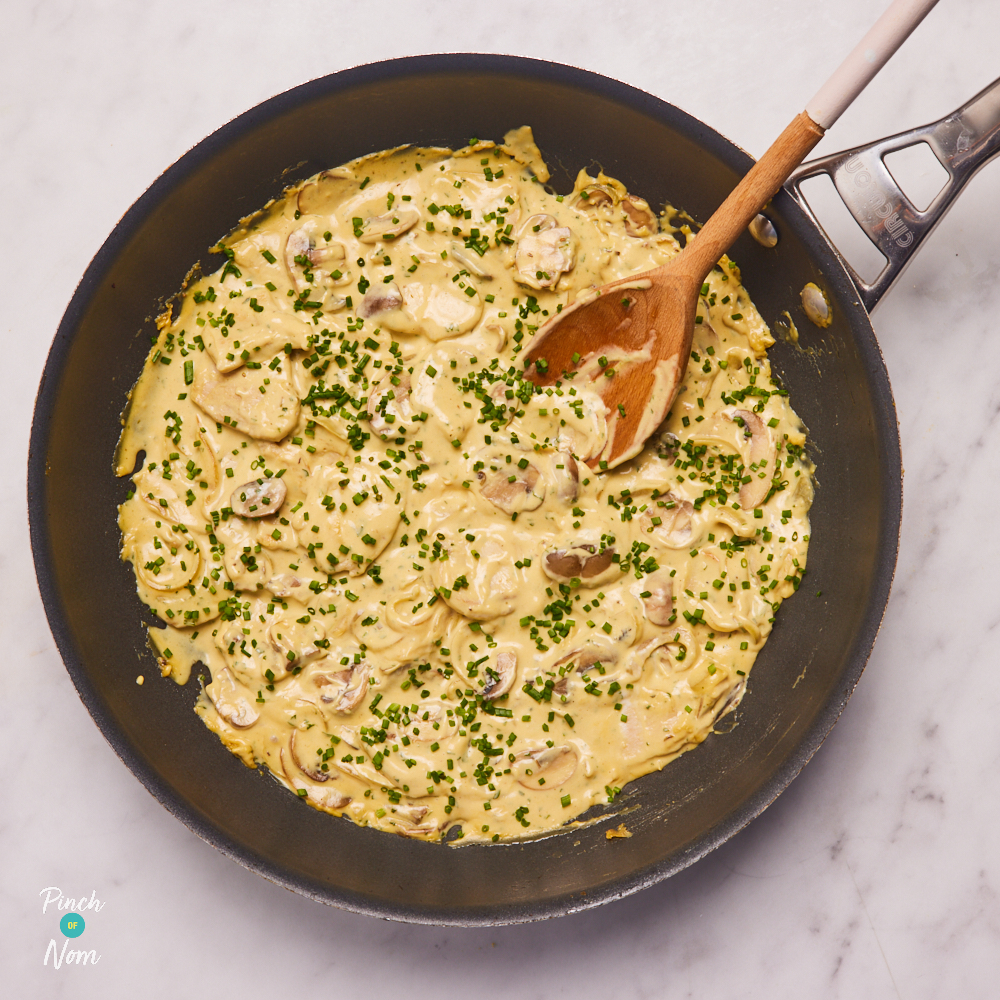 A wooden spoon rests in a pan of Flava It! X Pinch of Nom Creamy Garlic Chicken made with the recipe mix.