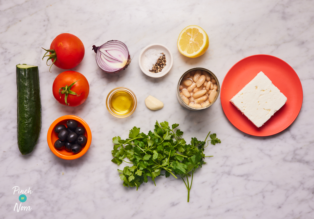 The ingredients for Pinch of Nom's Greek-Style Bean Salad are paid out on a kitchen surface. The ingredients are measured out into separate containers, ready to begin cooking.