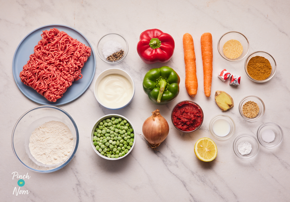 The ingredients for Pinch of Nom's Keema Naan Pies are laid out on a kitchen surface. Each ingredient is portioned out, ready to begin cooking.