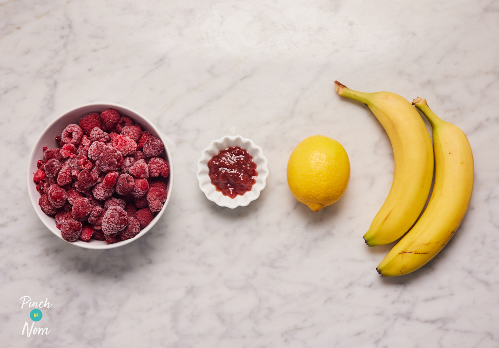 The ingredients for Pinch of Nom's low-calorie Raspberry Banana Ice Cream are laid out on a kitchen counter, ready to start cooking.