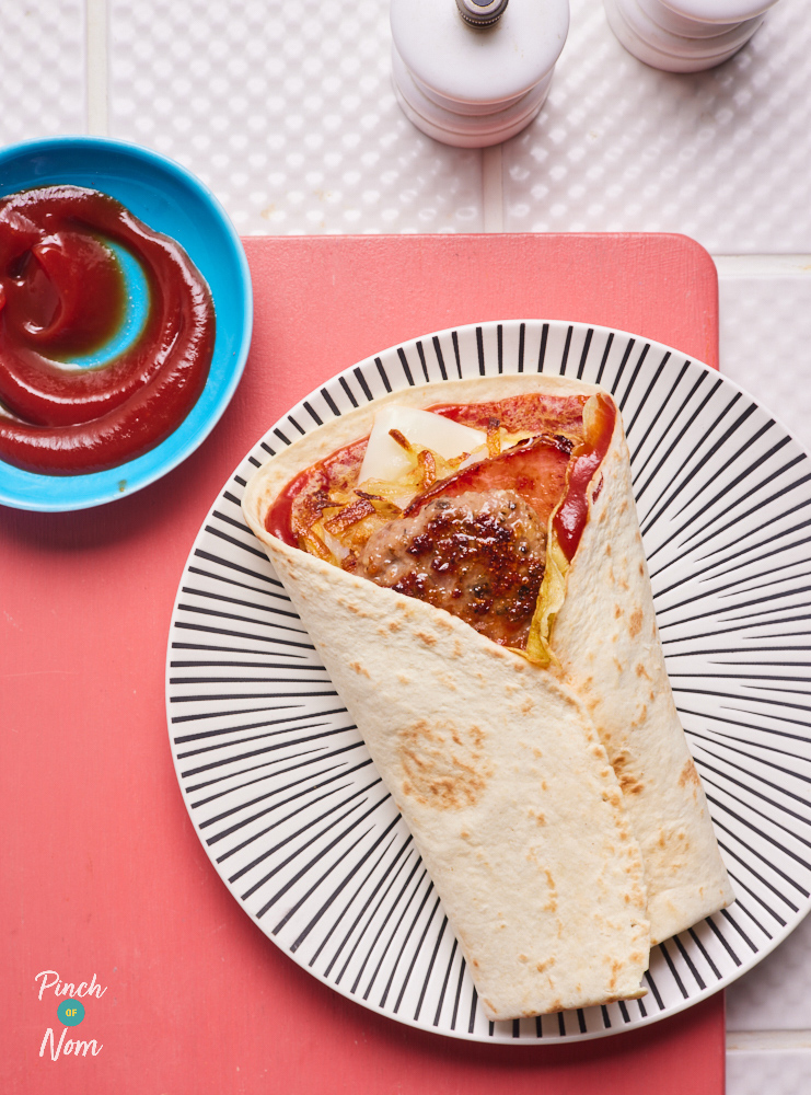 Pinch of Nom's Breakfast Wrap is served on a funky plate filled with sausage, bacon, cheese, egg and ketchup. There's extra ketchup in a small pot to the side, ready for dipping!