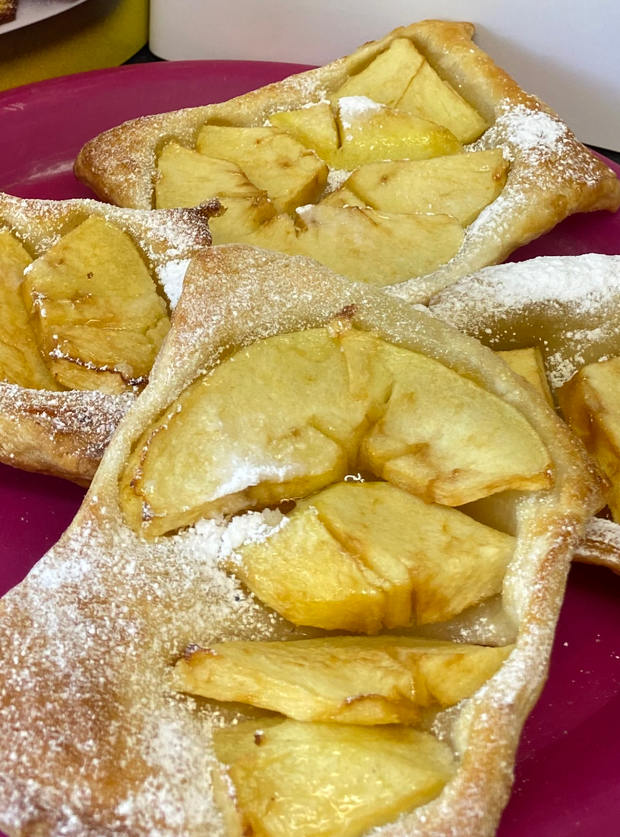 A freshly-baked batch of Pinch of Nom's Air Fryer Apple Upside Down Tarts (from page 192 of the Air Fryer cookbook) are laid out, waiting to be enjoyed, with juicy apple slices on top.