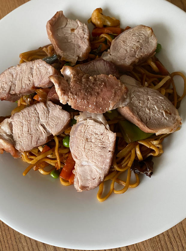 A portion of Pinch of Nom's Air Fryer Char-Siu-Style Pork Tenderloin is plated up on a bed of takeaway-inspired noodles.