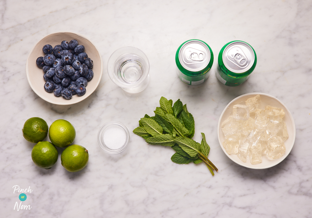 The ingredients for Pinch of Nom's Blueberry Mojito cocktail are laid out on a kitchen counter.