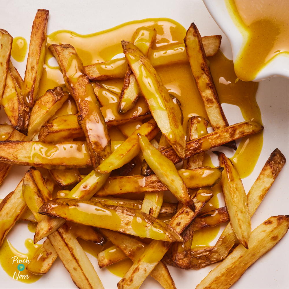 A close-up shows the Flava It! Chip Shop Curry Sauce being poured over a tray of golden chips.