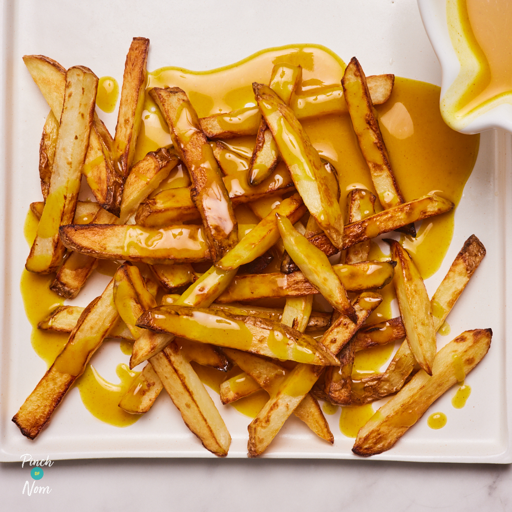 The Flava It! Chip Shop Curry Sauce being poured over a tray of golden chips.