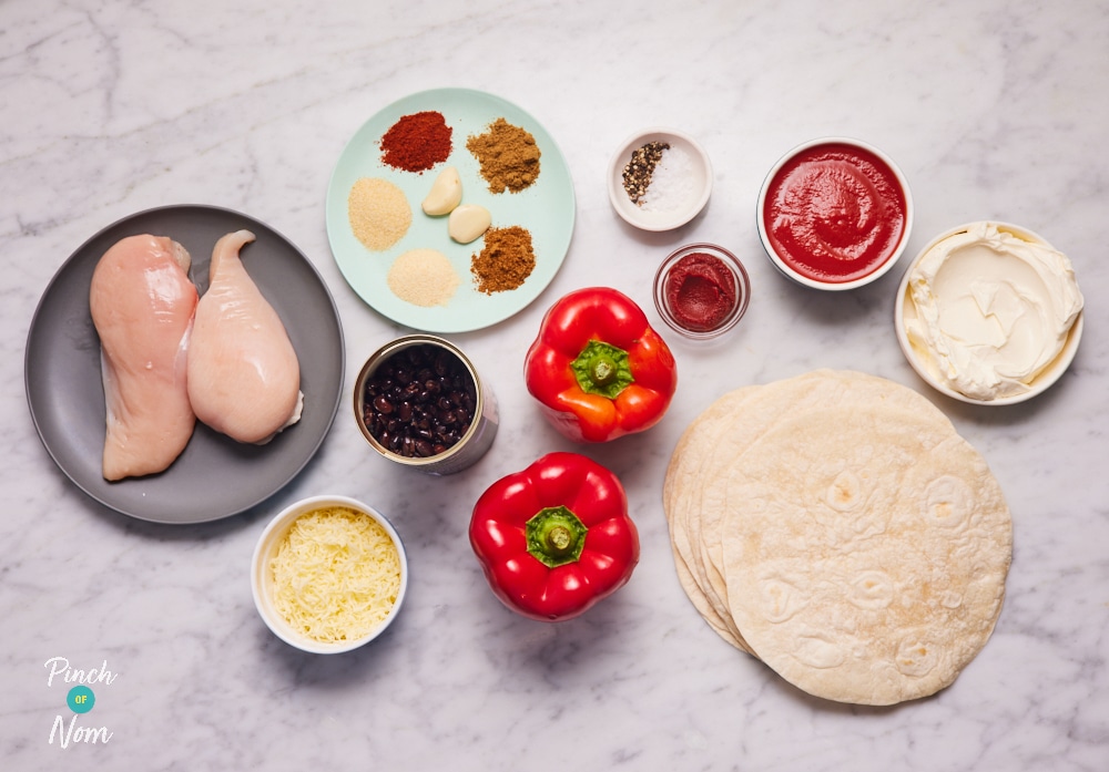 The ingredients for Pinch of Nom's slimming-friendly Creamy Chicken Enchiladas are laid out on a kitchen surface. Each ingredient is measured out, ready to begin cooking.