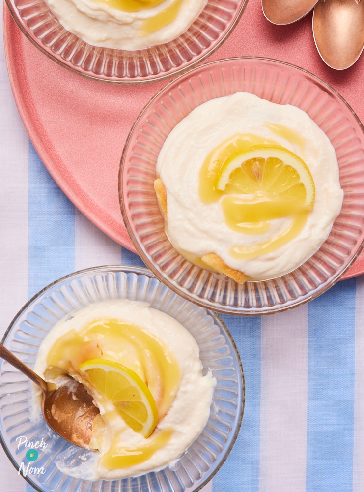 A close-up image of a table set with three individual-sized dessert dishes, filled with Pinch of Nom's Lemon Tiramisu recipe. Each portion is topped with a decorative lemon wedge.