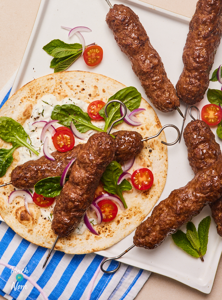 Pinch of Nom's Flava It! Burger and Kebab recipe mix has been used to make Seekh Kebabs. The kebabs are served on a flatbread, with lettuce leaves and cherry tomatoes.