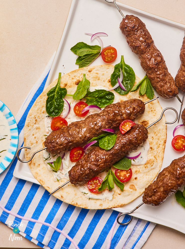 Pinch of Nom's Flava It! Burger and Kebab recipe mix has been used to make Seekh Kebabs. The kebabs are served on a flatbread, with lettuce leaves and cherry tomatoes.