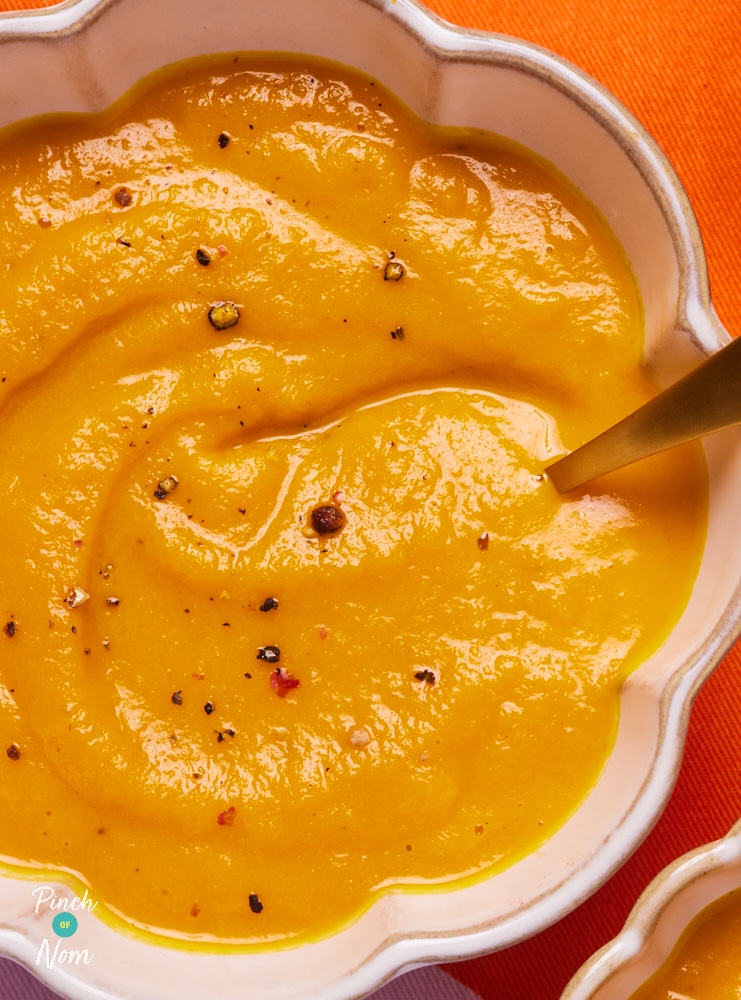 A close-up of a bowl of Pinch of Nom's Maple Roasted Carrot Soup; it's thick and smooth with a bright orange and yellow colouring.