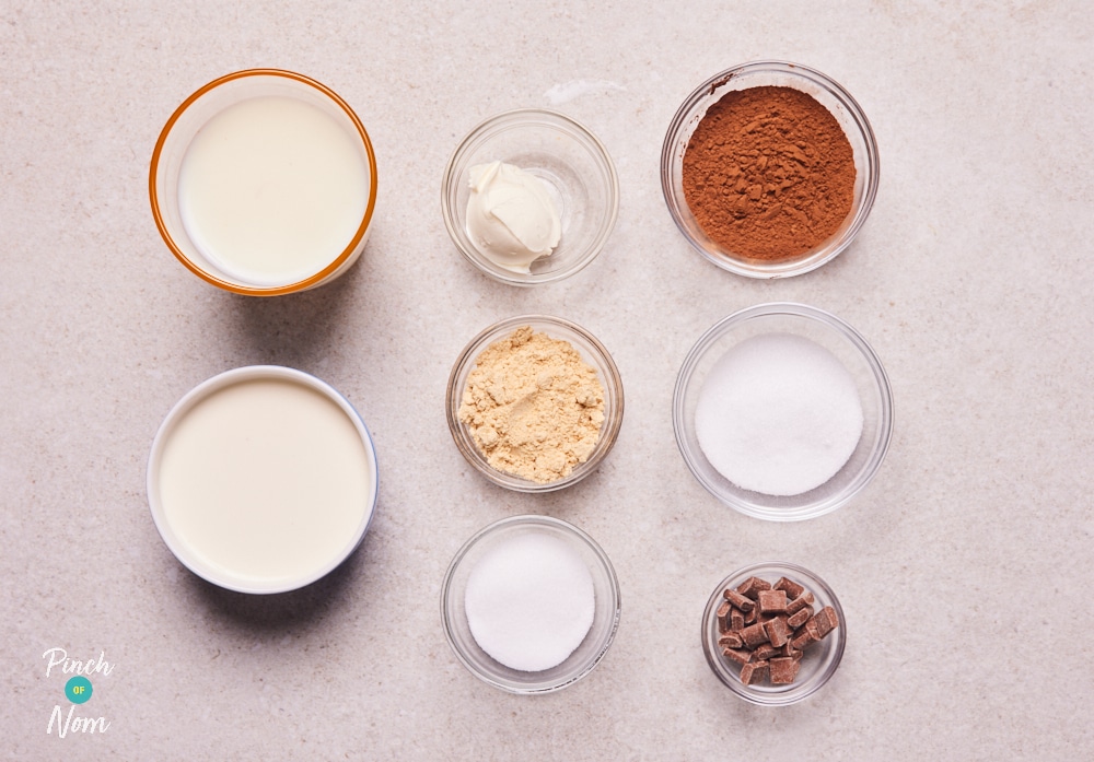 The ingredients for Pinch of Nom's low-calorie NInja Creami Peanut Butter and Chocolate Ice Cream are laid out on a kitchen counter, ready to begin making the recipe.